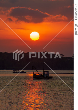 Beautiful golden sunset over the river with a small boat and sun reflection on the water. Beautiful golden sunset over the river with a small boat and sun reflection on the water. 140859426