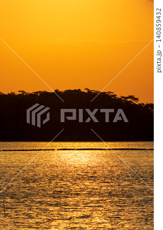 Beautiful golden sunset over the river with a small boat and sun reflection on the water. 140859432
