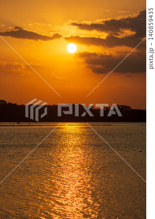 Beautiful golden sunset over the river with a small boat and sun reflection on the water. 140859435
