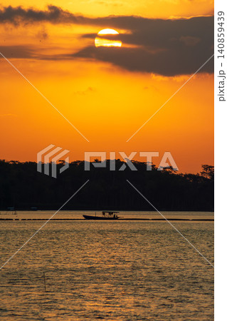 Beautiful golden sunset over the river with a small boat and sun reflection on the water. Beautiful golden sunset over the river with a small boat and sun reflection on the water. 140859439