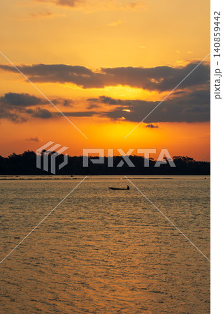 Beautiful golden sunset over the river with a small boat and sun reflection on the water. 140859442