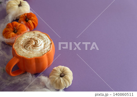 Pumpkin spice latte in pumpkin shaped mug with Halloween decoration Pumpkin spice latte in pumpkin shaped mug with Halloween decoration 140860511