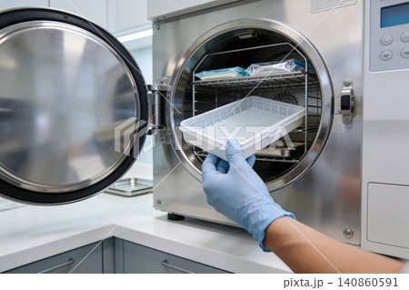 Dental professional sterilizing instruments in an autoclave for patient safety 140860591