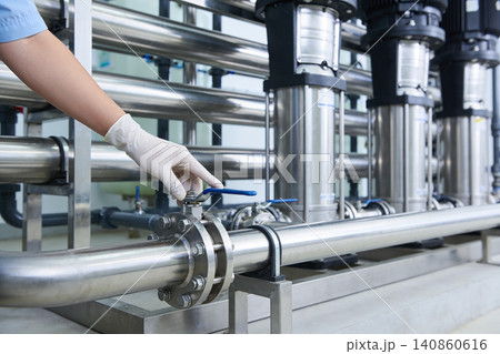 Worker in gloves adjusts valve on industrial water filtration system pipes Worker in gloves adjusts valve on industrial water filtration system pipes 140860616