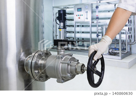 Gloved hand operating a large industrial valve in a clean water treatment facility 140860630