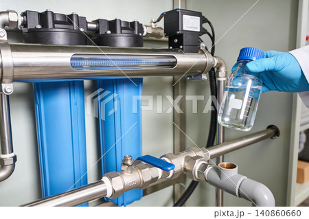 Scientist examines purified water sample from advanced filtration system Scientist examines purified water sample from advanced filtration system 140860660
