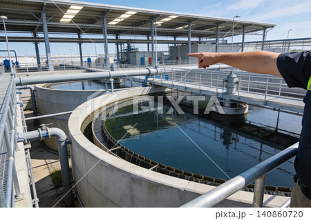 Water treatment plant clarifier tanks with a person pointing at the facility 140860720