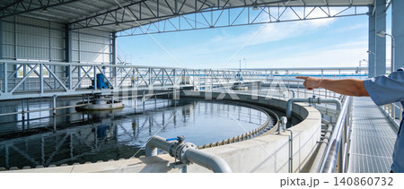 Wastewater treatment plant with a worker pointing towards the circular clarifier Wastewater treatment plant with a worker pointing towards the circular clarifier 140860732