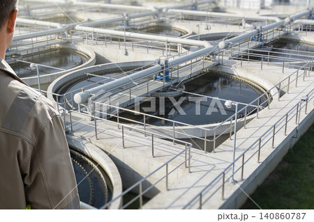 Engineer observing circular clarifier tanks at a modern water treatment facility Engineer observing circular clarifier tanks at a modern water treatment facility 140860787