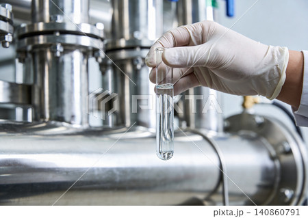 Scientist holding a test tube with clear liquid in a laboratory setting Scientist holding a test tube with clear liquid in a laboratory setting 140860791