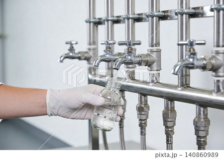Scientist collecting liquid sample from laboratory faucet into glass bottle Scientist collecting liquid sample from laboratory faucet into glass bottle 140860989