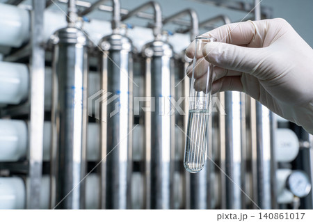 Scientist examines liquid sample in test tube at water purification plant Scientist examines liquid sample in test tube at water purification plant 140861017