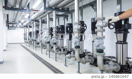 Industrial pump room with multiple pumps and extensive piping system Industrial pump room with multiple pumps and extensive piping system 140861047