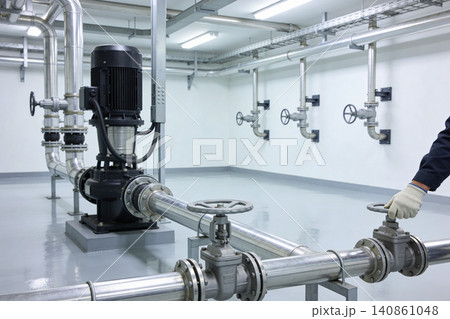 Industrial pump and valve system in a clean, modern facility with bright lighting 140861048