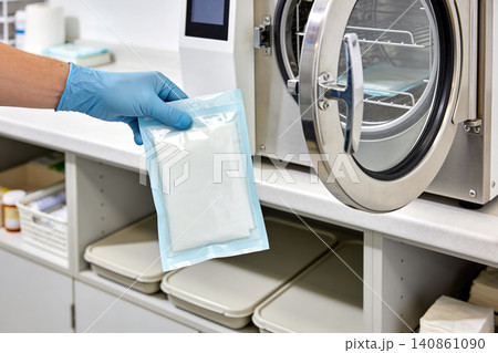 Healthcare professional places sterile packaged medical instruments into an autoclave Healthcare professional places sterile packaged medical instruments into an autoclave 140861090