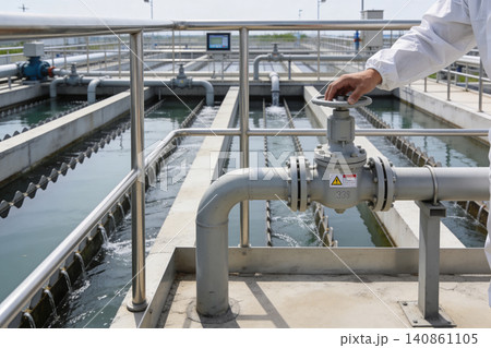 Operator adjusts valve at water treatment plant with cascading water channels Operator adjusts valve at water treatment plant with cascading water channels 140861105