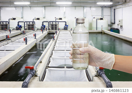 Scientist holding a sample of clear liquid in a laboratory setting 140861123