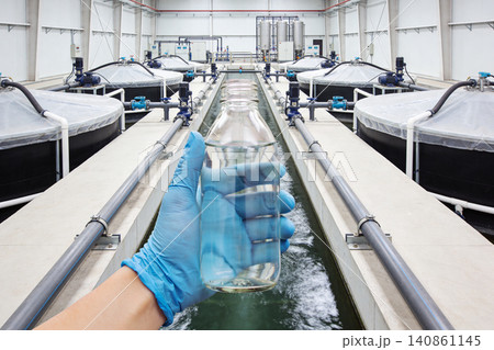 Scientist holding sample of purified water in industrial treatment facility 140861145