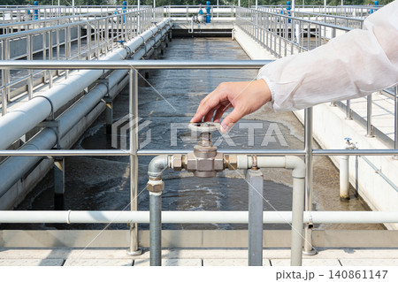 Operator adjusts valve controlling water flow in industrial treatment plant 140861147