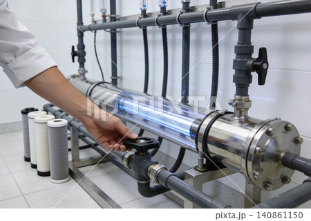 Technician adjusts valve on UV water purification system with glowing lamp Technician adjusts valve on UV water purification system with glowing lamp 140861150