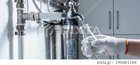 Laboratory technician collecting water sample from filtration system into flask Laboratory technician collecting water sample from filtration system into flask 140861168