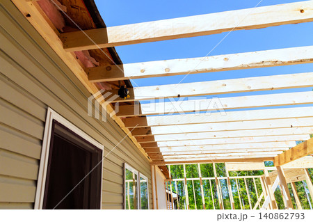 Workers build wooden frame for new beams structure next to house with frameworks Workers build wooden frame for new beams structure next to house with frameworks 140862793
