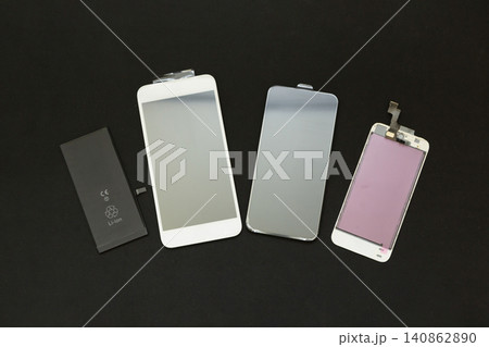 黒い背景に並べたスマートフォンのバッテリーと画面パーツ 140862890
