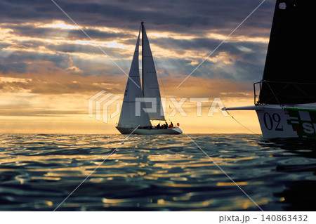 A lot of sailing boats are in sailing regatta in the Gulf of Finland at sunset, Russia, St.Petersburg, hot race of several yachts, teamwork, yachtsman 140863432