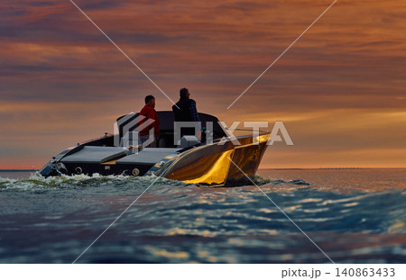 Incredible reflection on the glossy side of a modern motorboat at sunset, the Gulf of Finland, magic reflections on water surface Incredible reflection on the glossy side of a modern motorboat at sunset, the Gulf of Finland, magic reflections on water surface 140863433