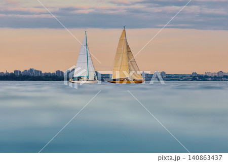 A lot of sailing boats are in sailing regatta in the Gulf of Finland at sunset, Russia, St.Petersburg, hot race of several yachts, teamwork, yachtsman 140863437