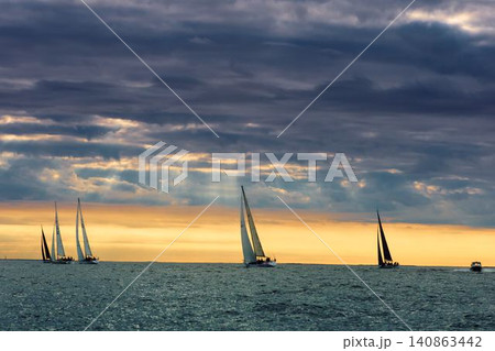 A lot of sailing boats are in sailing regatta in the Gulf of Finland at sunset, Russia, St.Petersburg, hot race of several yachts, teamwork, yachtsman A lot of sailing boats are in sailing regatta in the Gulf of Finland at sunset, Russia, St.Petersburg, hot race of several yachts, teamwork, yachtsman 140863442