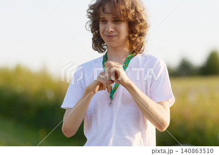 Teenager boy with long curly hair wearing sunflower lanyard 140863510