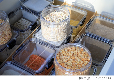 Clear plastic containers are filled with flour and grains. Well-organized kitchen cabinet drawer holds various dry goods in airtight food boxes 140863743