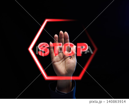 Raised female palm behind glowing red neon STOP sign 140863914