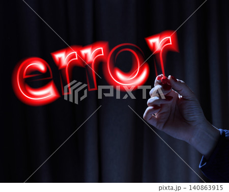 A woman's hand writes the word error in red neon light in the air against a dark background. A woman's hand writes the word error in red neon light in the air against a dark background. 140863915