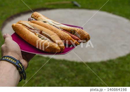 Grilling hot dogs in a backyard during a summer barbecue gathering Grilling hot dogs in a backyard during a summer barbecue gathering 140864198