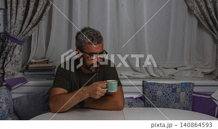 Man enjoys coffee while working at home on weekend Man enjoys coffee while working at home on weekend 140864593