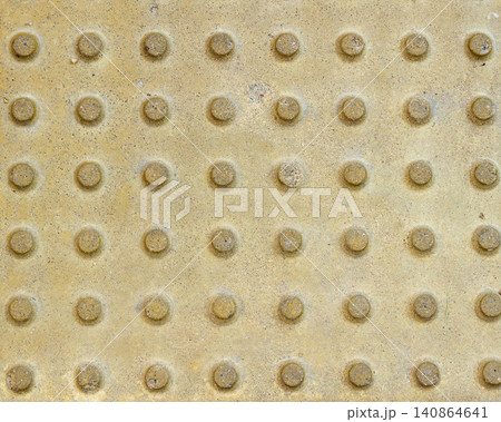 Top view of yellow tactile paving tiles with truncated domes for visually impaired navigation. 140864641