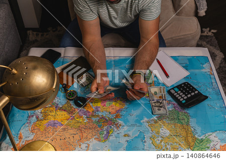 Planning a travel budget while counting cash on a world map Planning a travel budget while counting cash on a world map 140864646