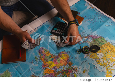Planning travel budget with cash, calculator, and a map on the table Planning travel budget with cash, calculator, and a map on the table 140864647