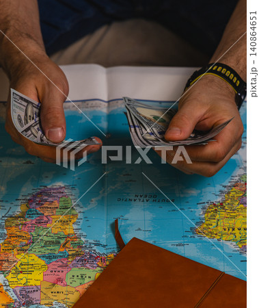 Planning a travel budget with cash and a world map for the upcoming trip Planning a travel budget with cash and a world map for the upcoming trip 140864651