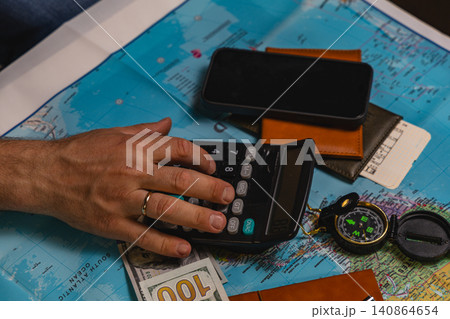 Budget calculation using calculator on a world map with travel items 140864654