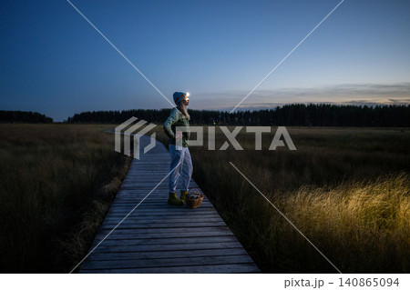 Woman forager taking moment to enjoy sunset on way home returning late from spending day in forest. 140865094