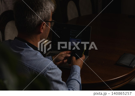 Working late at night with laptop and smartphone in home office Working late at night with laptop and smartphone in home office 140865257