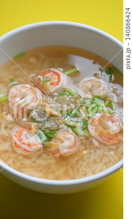 rice soup with shrimp in white bowl on yellow background rice soup with shrimp in white bowl on yellow background 140866424