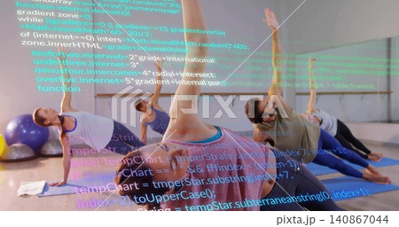Performing side-plank, woman in pink tank top with five classmates on blue mats, code overlay 140867044