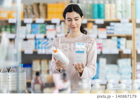 Girl in autumn clothes choosing skin cream at drugstore 140867179