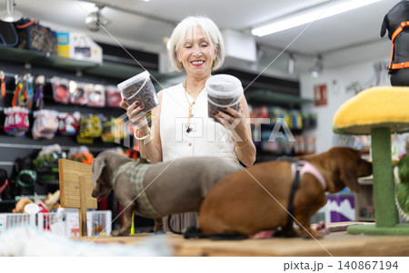Elderly woman choosing dog food in pet store Elderly woman choosing dog food in pet store 140867194
