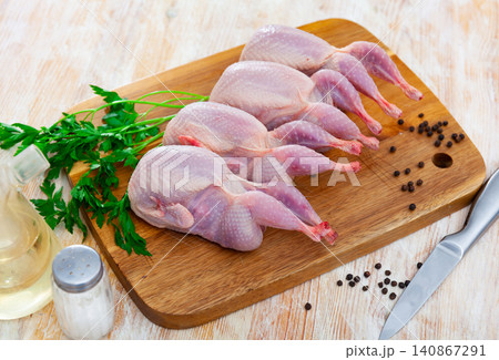 Raw gutted partridges on wooden table with seasonings and greens Raw gutted partridges on wooden table with seasonings and greens 140867291