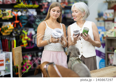 elderly woman stands in a pet store with a teenage girl and chooses food elderly woman stands in a pet store with a teenage girl and chooses food 140867297